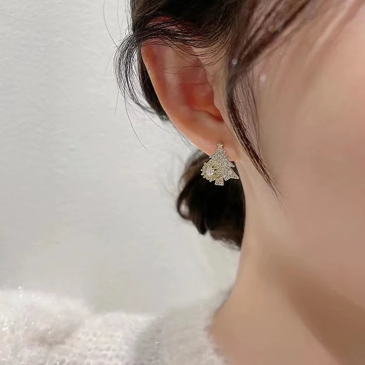 Pair of rotatable Christmas tree stud earrings with rhinestone snowflake detail in gold on a white background