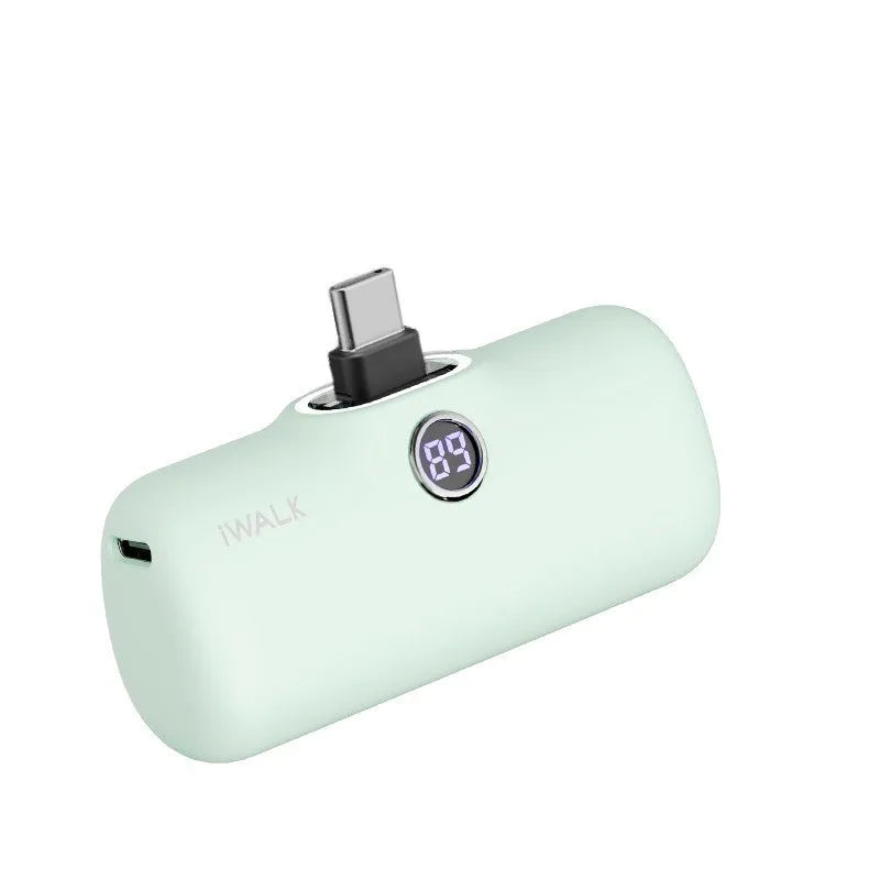 Compact white lipstick-shaped power bank with digital battery percentage display on a wooden table.