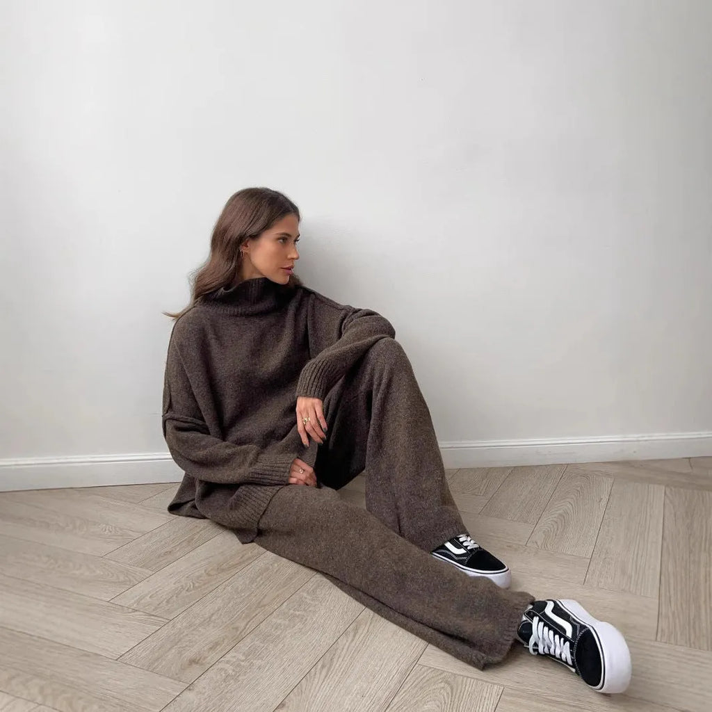 Women's dark grey acrylic knitted lounge suit with side-slit sweater and matching trousers on a hanger.