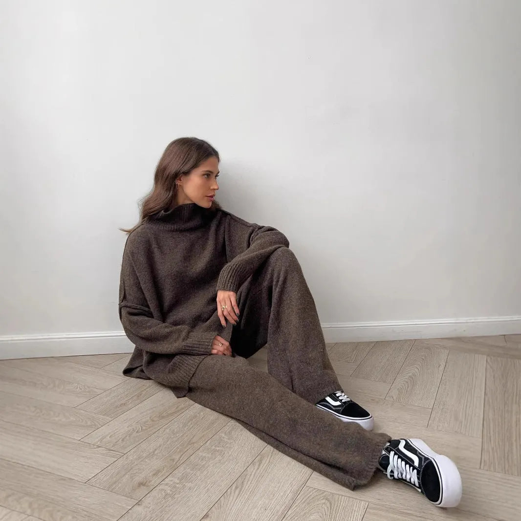 Women's dark grey acrylic knitted lounge suit with side-slit sweater and matching trousers on a hanger.