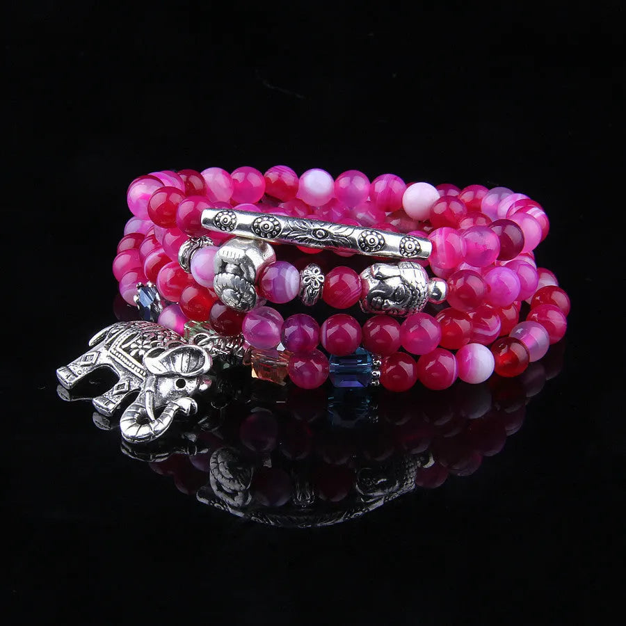 Multi-layer agate bracelet with blue elephant pattern amulet on a wrist.