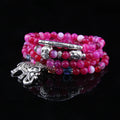 Multi-layer agate bracelet with blue elephant pattern amulet on a wrist.