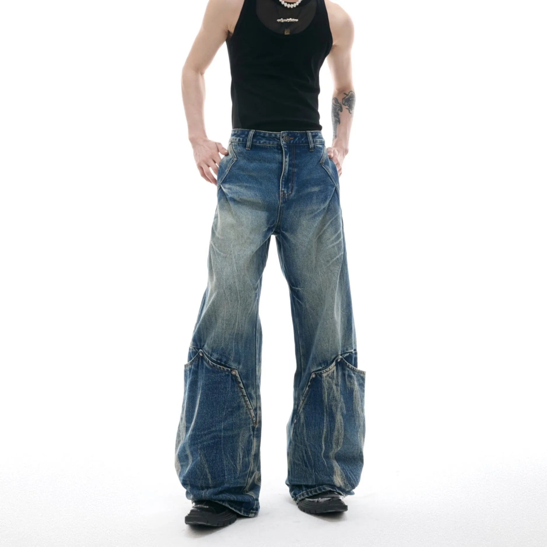 Man wearing verdant blue loose-fit curved knife jeans with a retro washed burst pattern, showing front and side view.