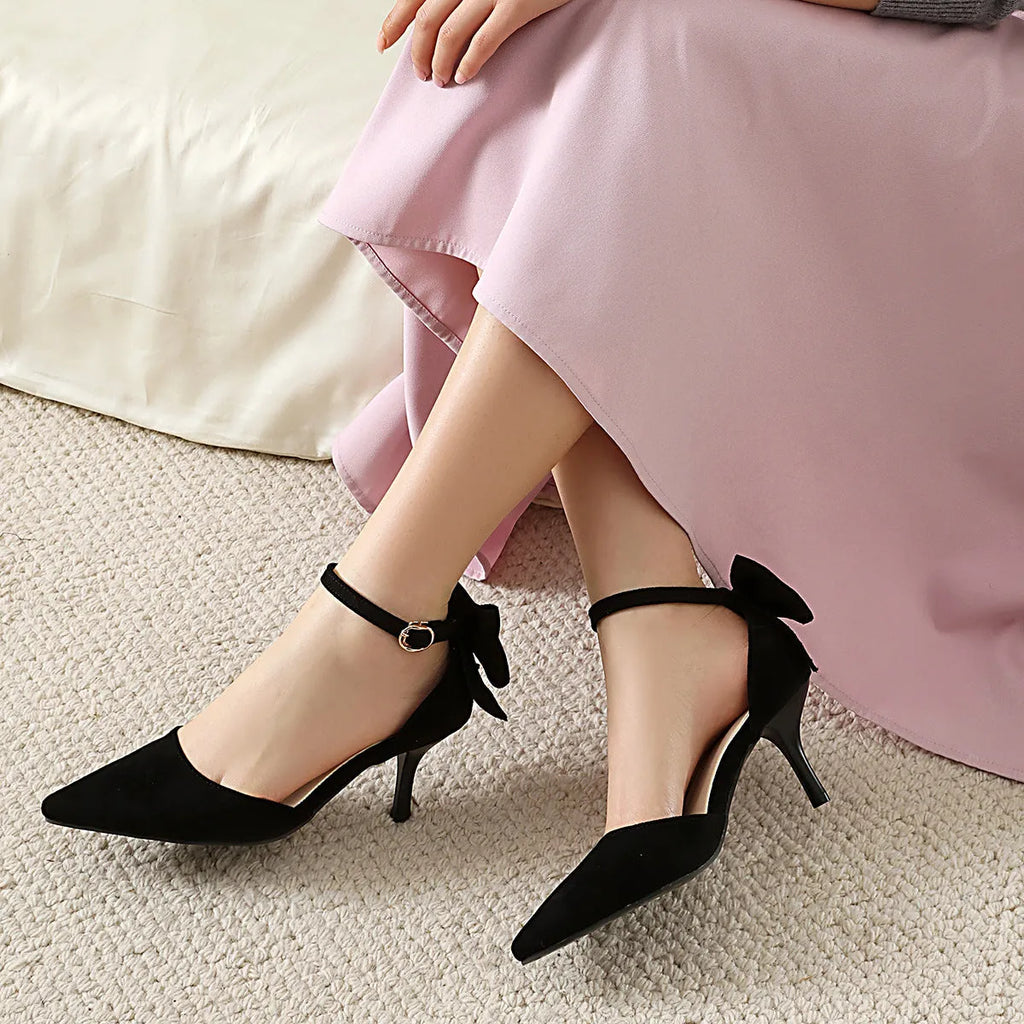 Black suede women's stiletto heels with a pointed toe and a decorative bowknot on the upper.