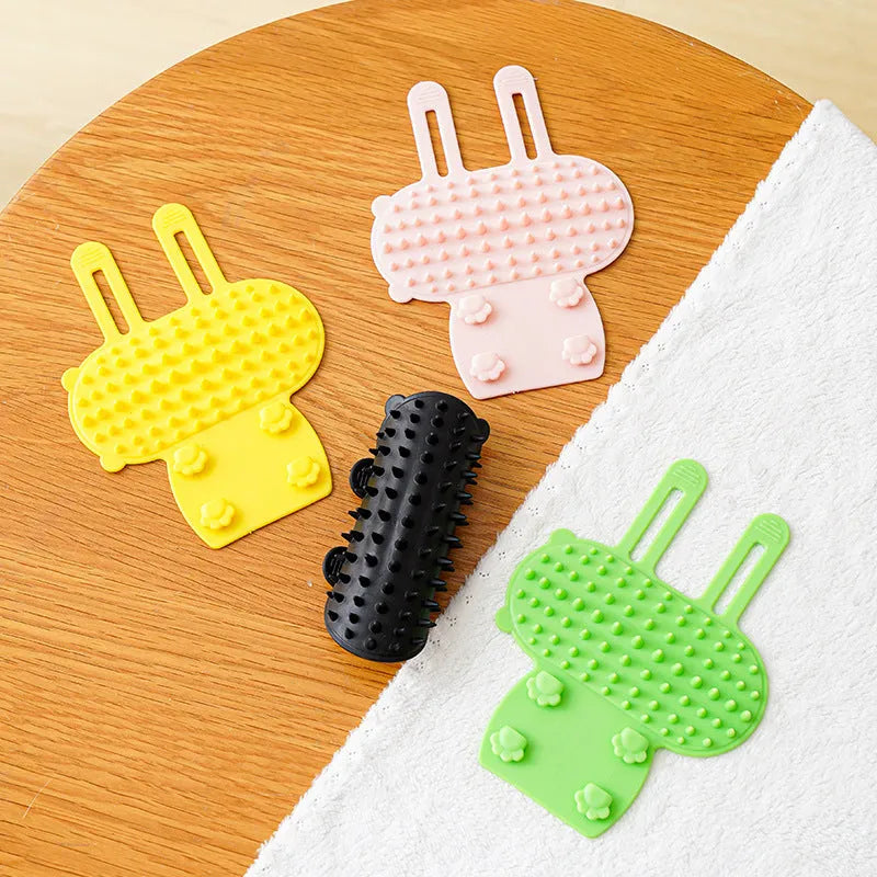 Silicone cat grooming comb with adjustable strap mounted on a furniture leg