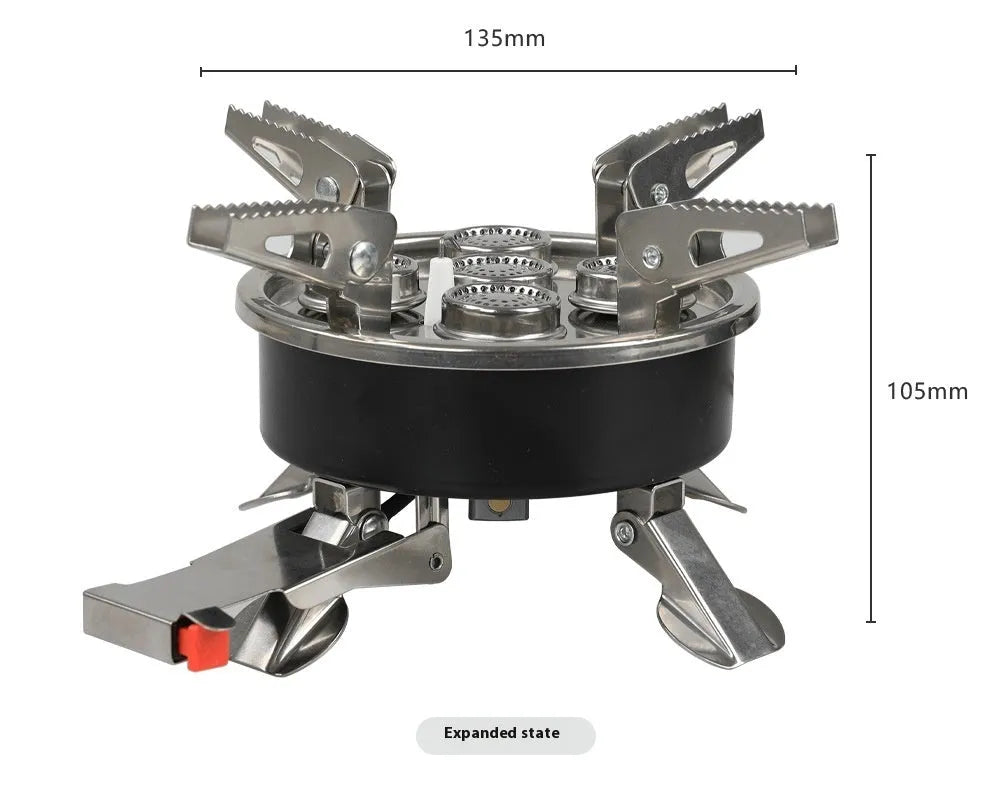 Silver portable folding camping stove with extended copper gas hose, shown on a wooden picnic table.