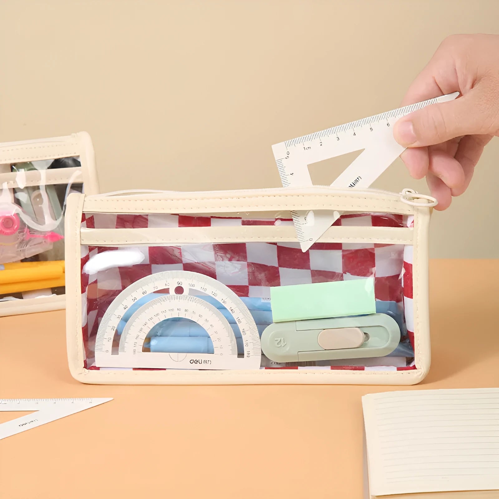 Clear PVC pencil case with black and white chessboard grid design, showing pens inside.