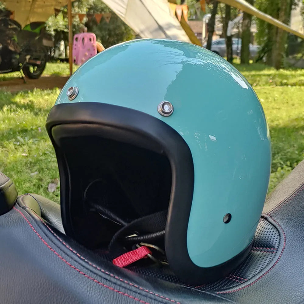 Retro-style open-face motorcycle helmet in fibreglass, shown in a choice of colours including Cement Grey and Matte Black Flower.