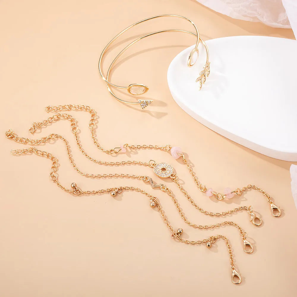 Set of six gold bracelets with arrow, water drop, and V shapes featuring spot drill detail.