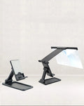 Black folding mobile phone screen magnifier and detachable phone holder on a desk.