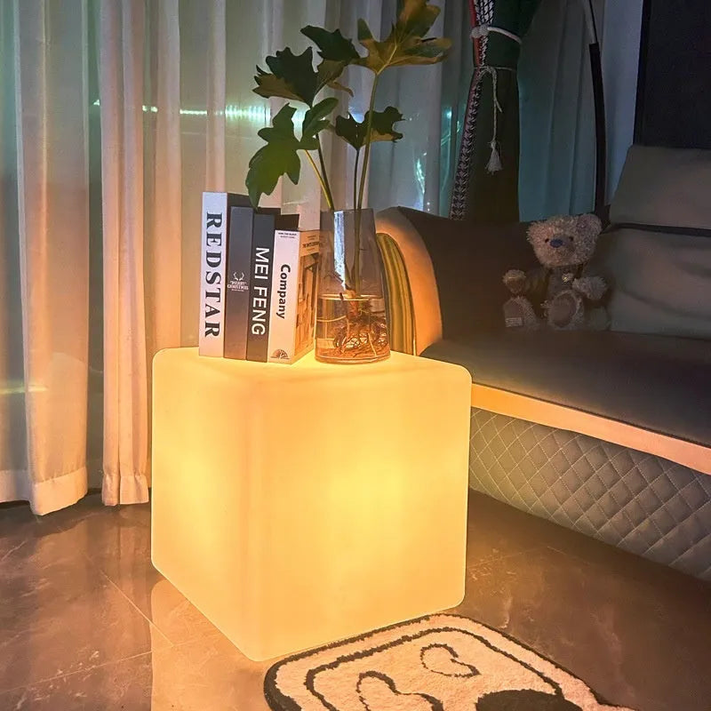 Modern square LED cube light stool in a garden setting, showcasing its clean design and luminous top.