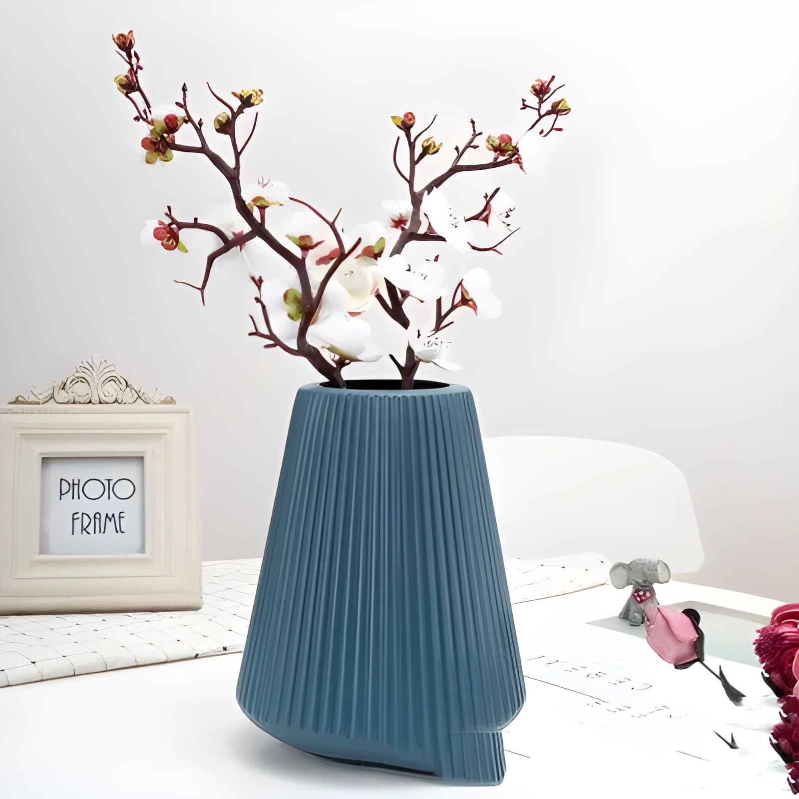Colourful melamine plastic flower vase in blue, green, pink, or white on a desk.