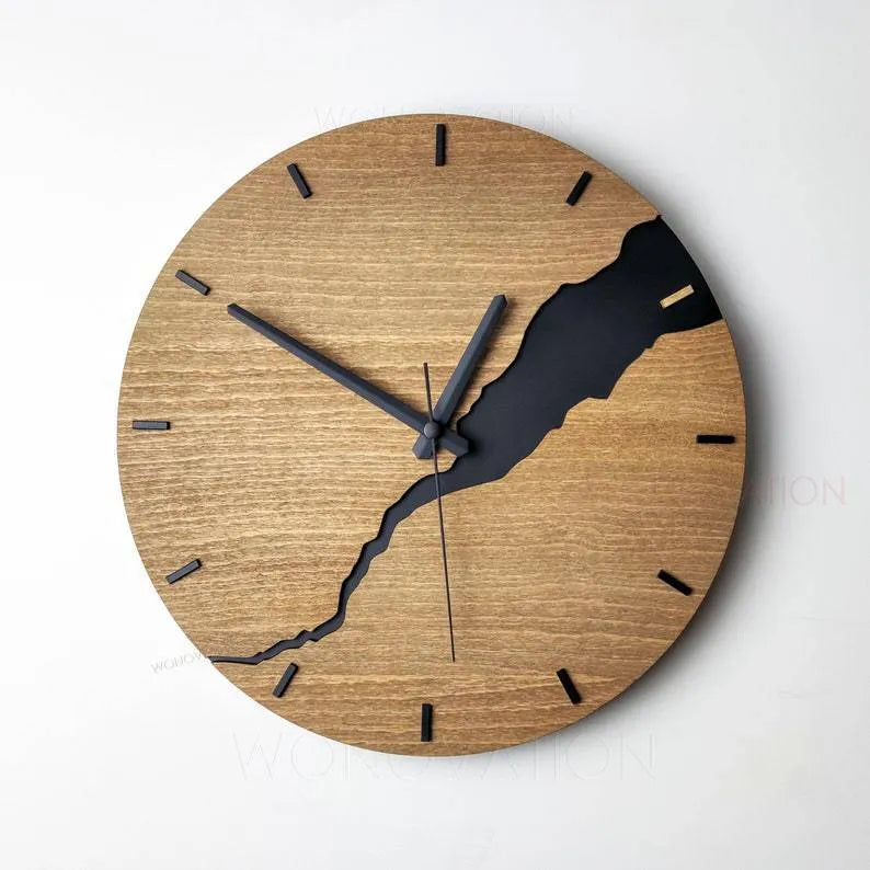 Modern simple wooden wall clock with a crack design dial on a light wood background.