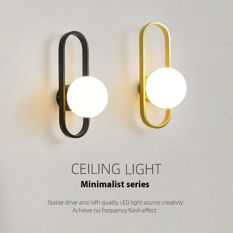 Minimalist black iron wall sconce lamp with glass shade mounted beside a bed.