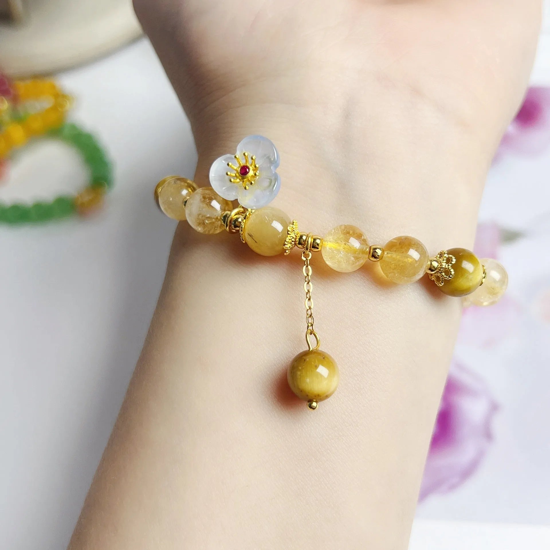 Close-up of a handcrafted citrine crystal bracelet for women with a floral tassel pendant.