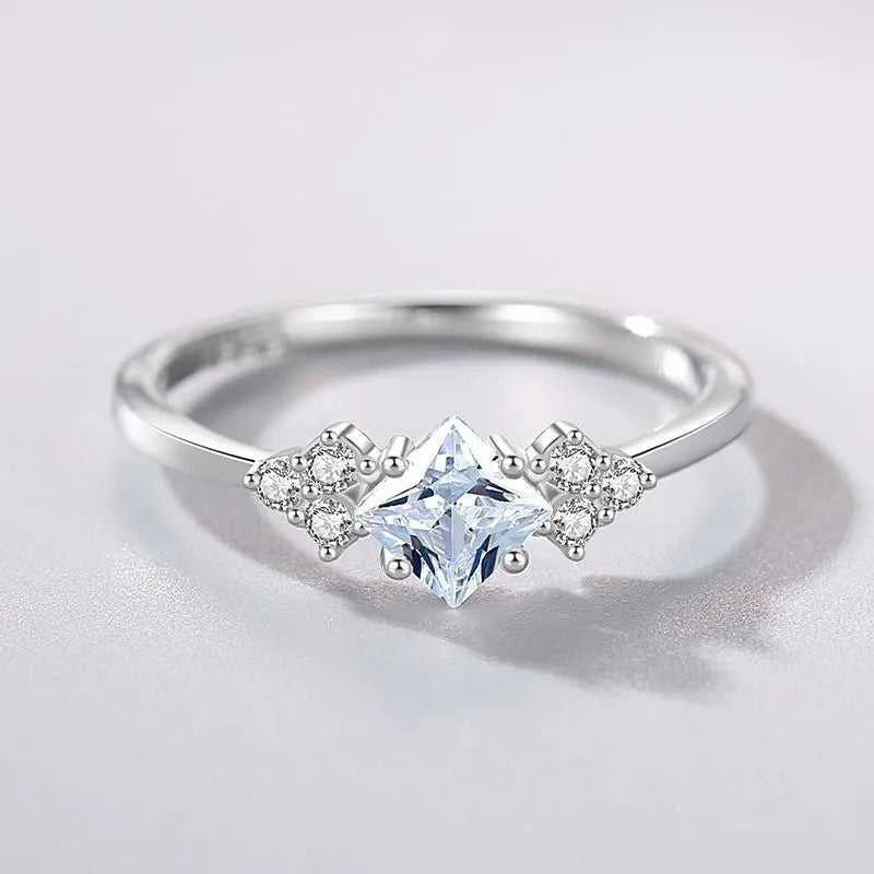 S925 silver ring with rhombus-shaped gold-plated setting and artificial gem on white background