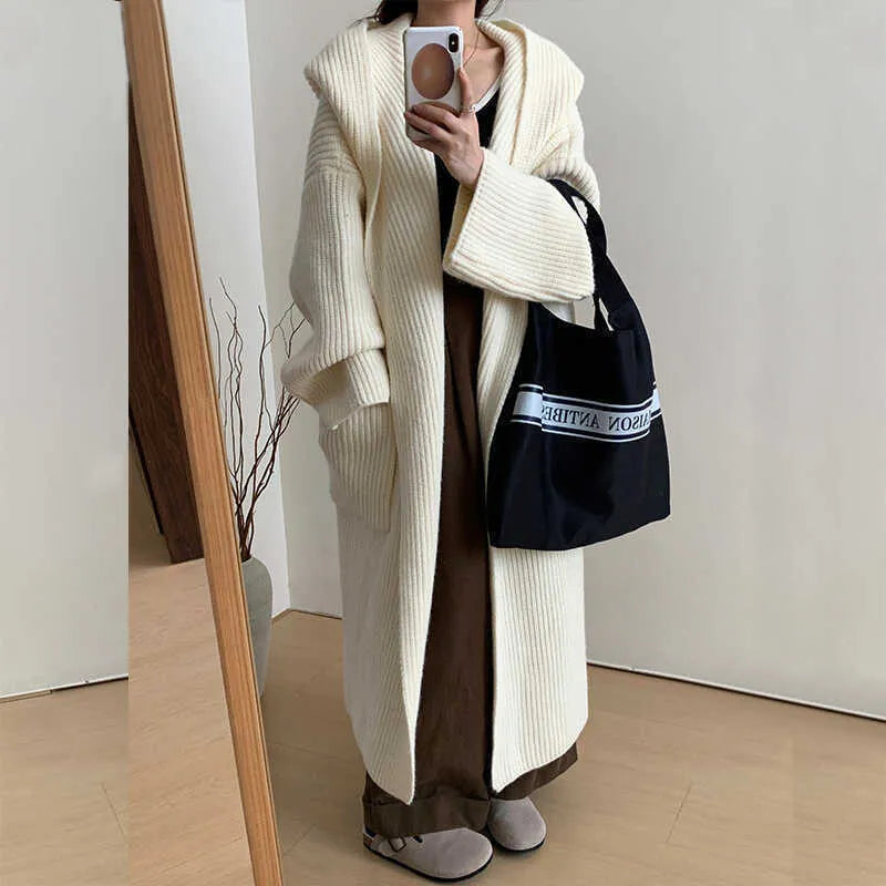 A woman wearing a loose, milky white hooded cardigan coat with raglan sleeves.