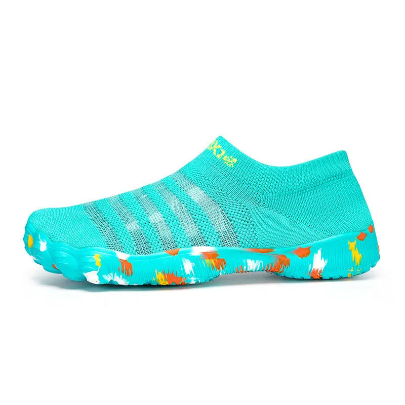 Women's camouflage pattern water shoes with Flyknit upper and flat rubber sole on a rocky shore.