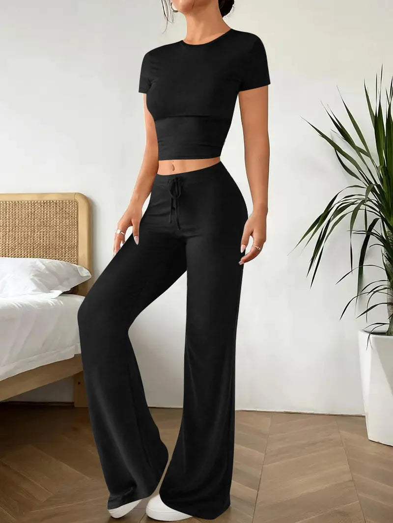 Black high-waist polyester trousers and matching short-sleeve t-shirt laid flat as a two-piece suit set.