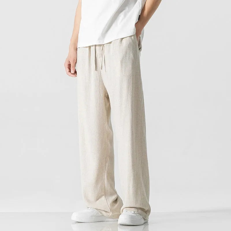 Man wearing beige straight-leg cropped bamboo fibre trousers with a drawstring waist on a summer day.