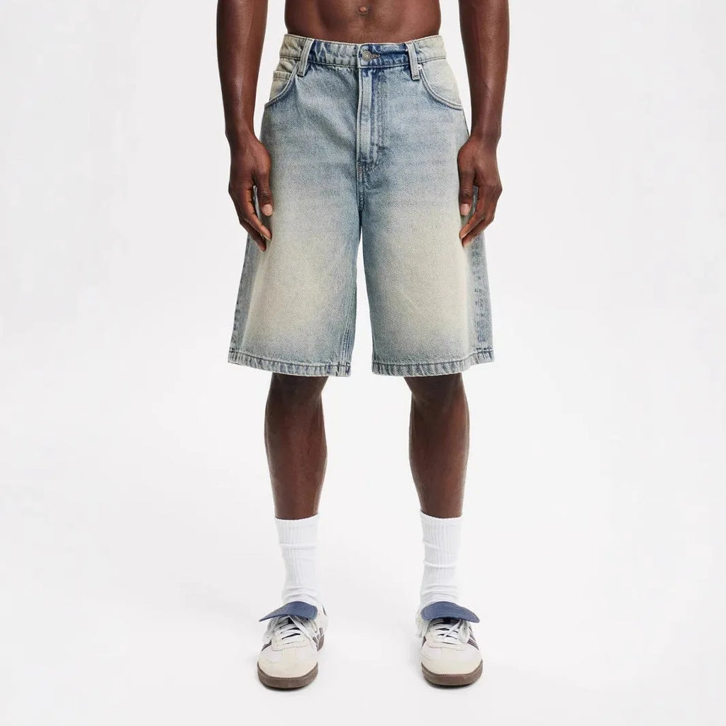 Man wearing loose fit light blue straight leg denim jeans on a street.