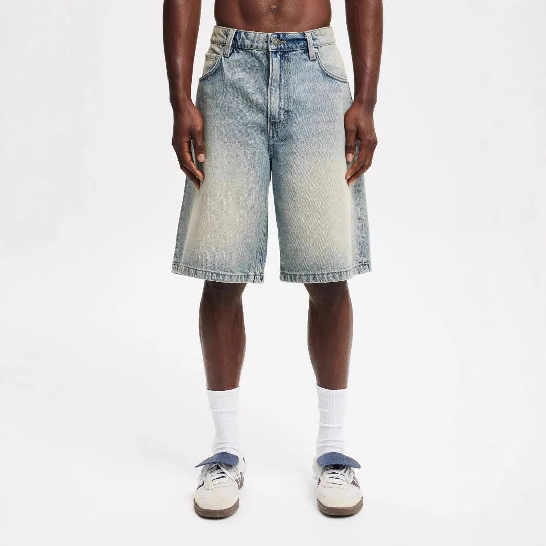 Man wearing loose fit light blue straight leg denim jeans on a street.