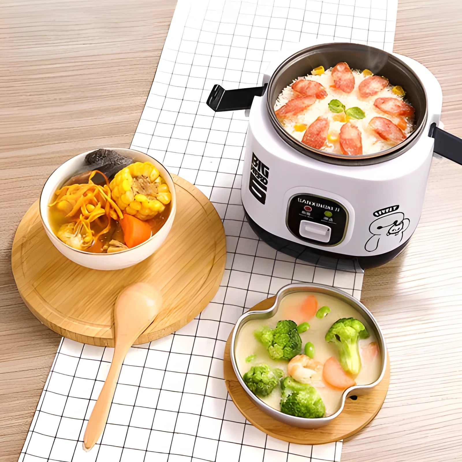 Small round blue and black miniature automatic rice cooker with steam pan on a kitchen counter.