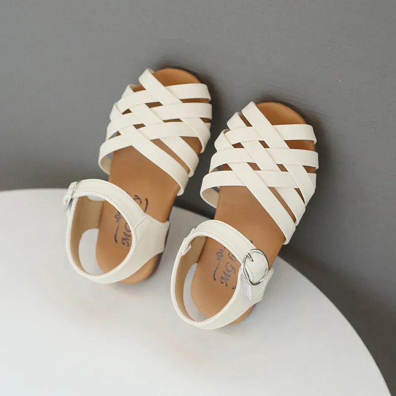 Kids buckle-toe soft sole woven sandals in white, black, and pink on a light background