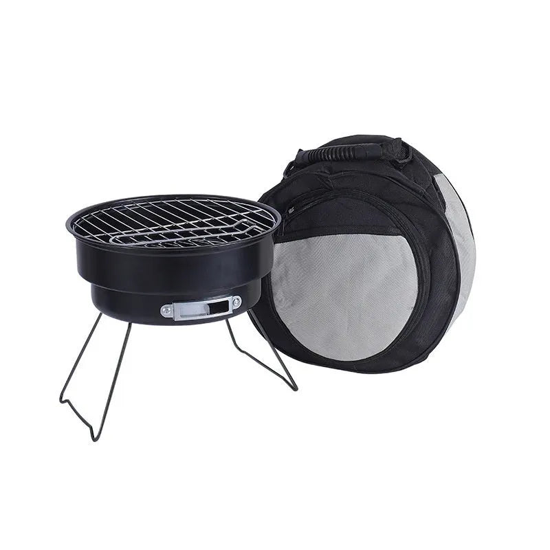 Small round metal folding stove with barbecue grill and mesh, set up for outdoor cooking.