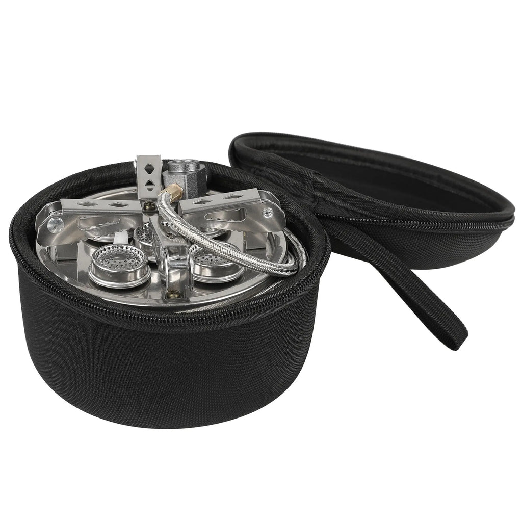 Silver portable folding camping stove with extended copper gas hose, shown on a wooden picnic table.