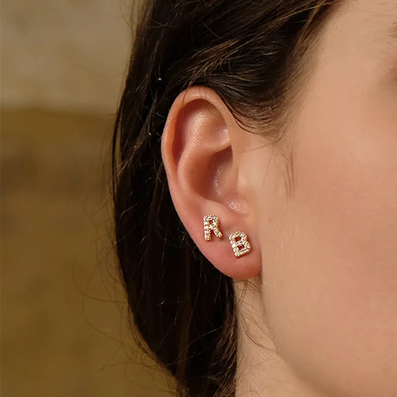 Gold plated copper stud earrings showing a single English letter, part of a full alphabet set.