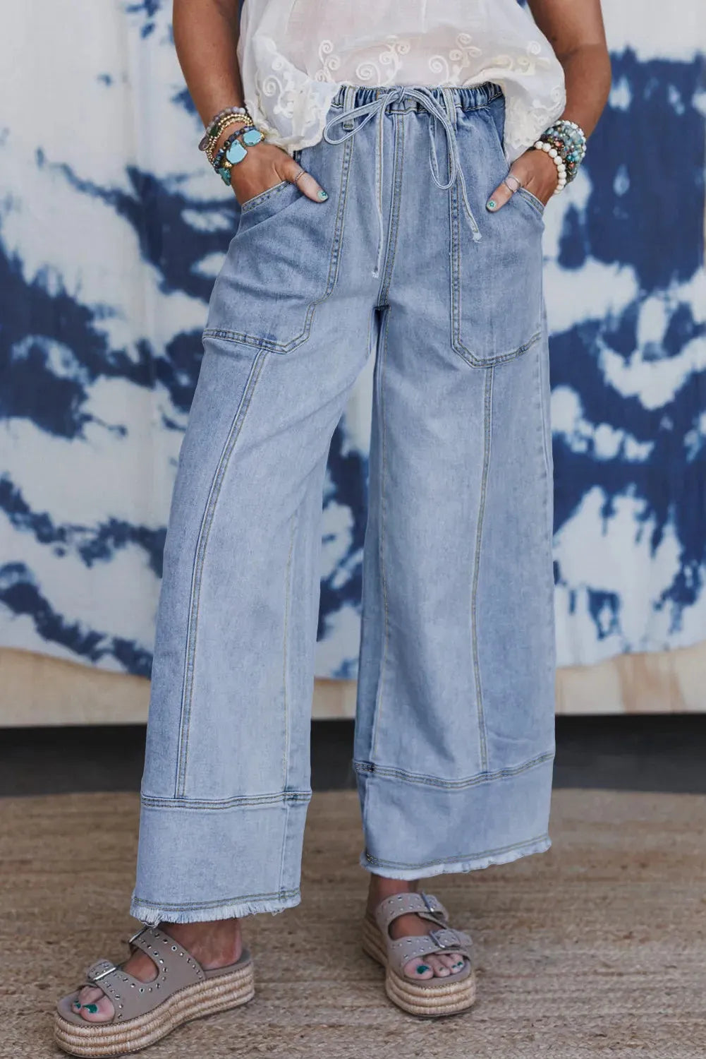Beau blue women's wide-leg denim trousers with a drawstring waistband and raw hem detail.