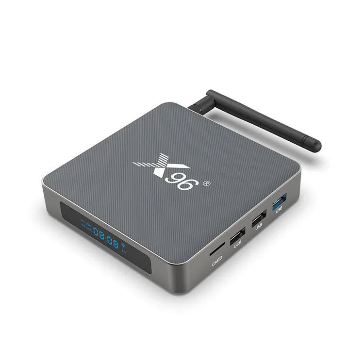 Android smart TV set-top box with voice remote control on a wooden table next to a television.