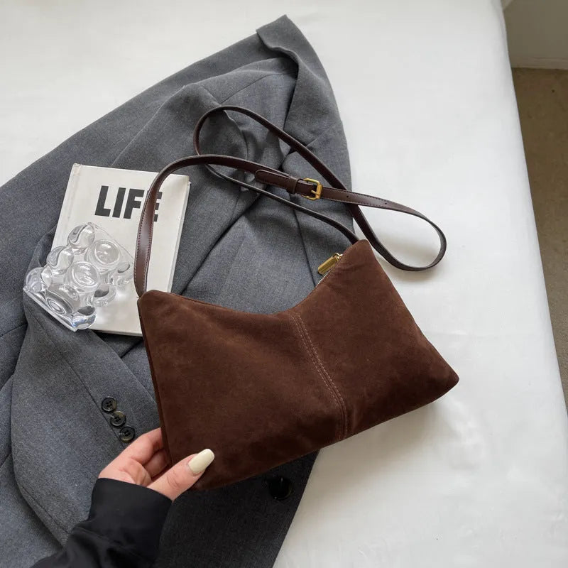 Retro brown suede underarm bucket bag with visible sewing line detail on a woman's shoulder during commute