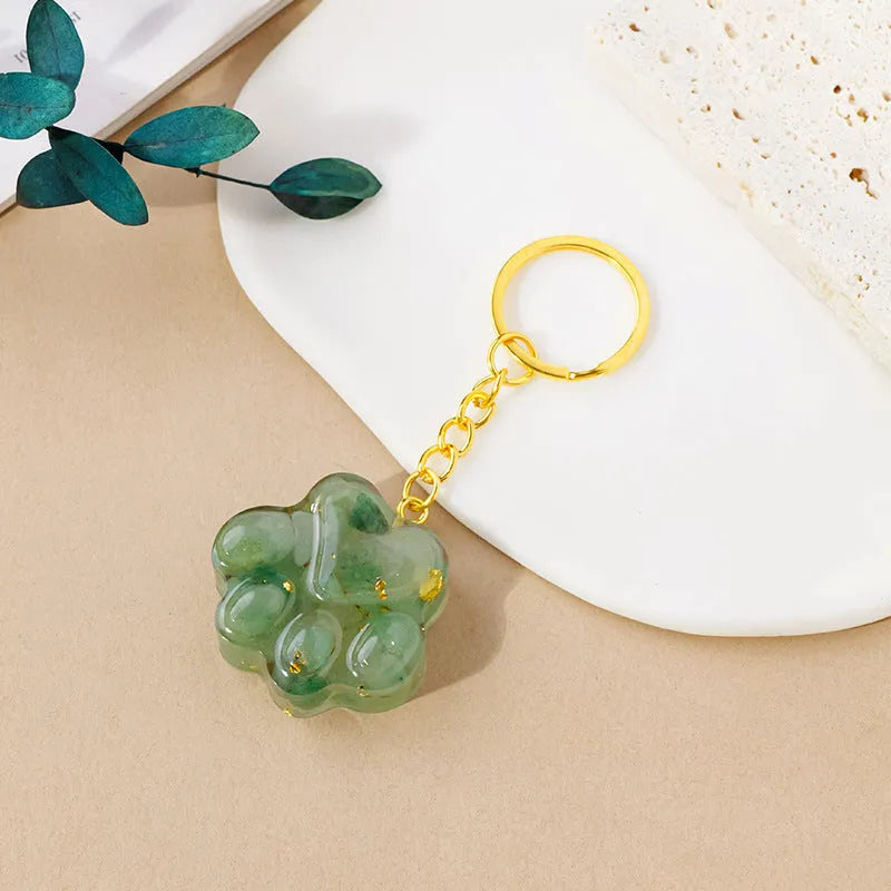 Hand-finished natural crystal cat's paw keychain pendant on a metal ring, showing detailed carving and polished stone surface.