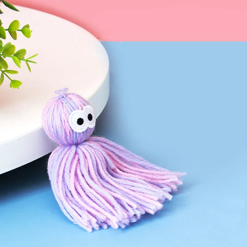Four wool cat balls with hanging loops and teaser stick in blue grey, pink and blue, and pink purple colours