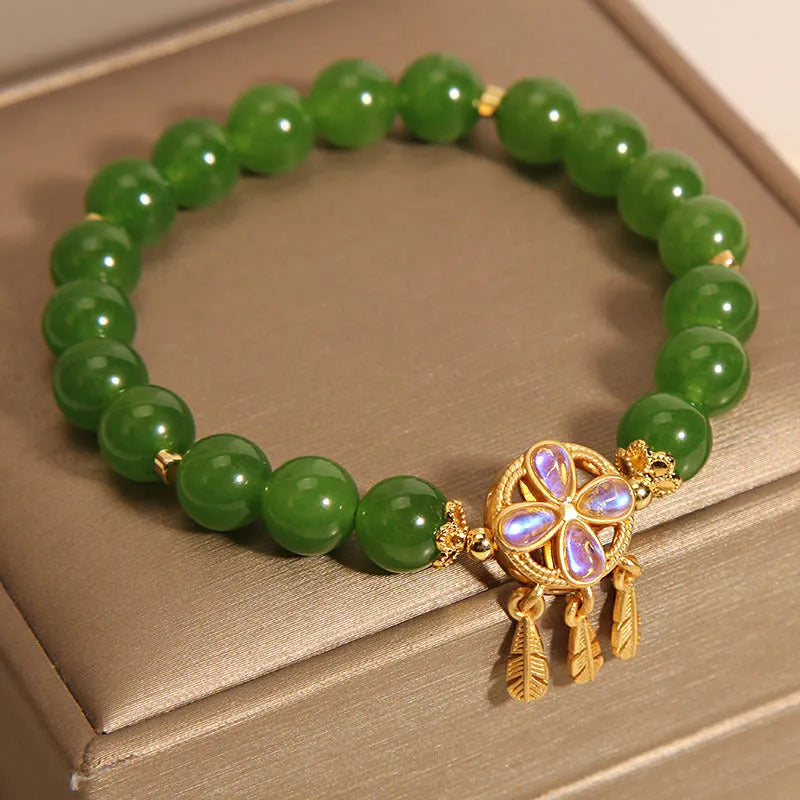 Green Jasper crystal bracelet with a four-leaf clover dream catcher pendant on a woman's wrist.