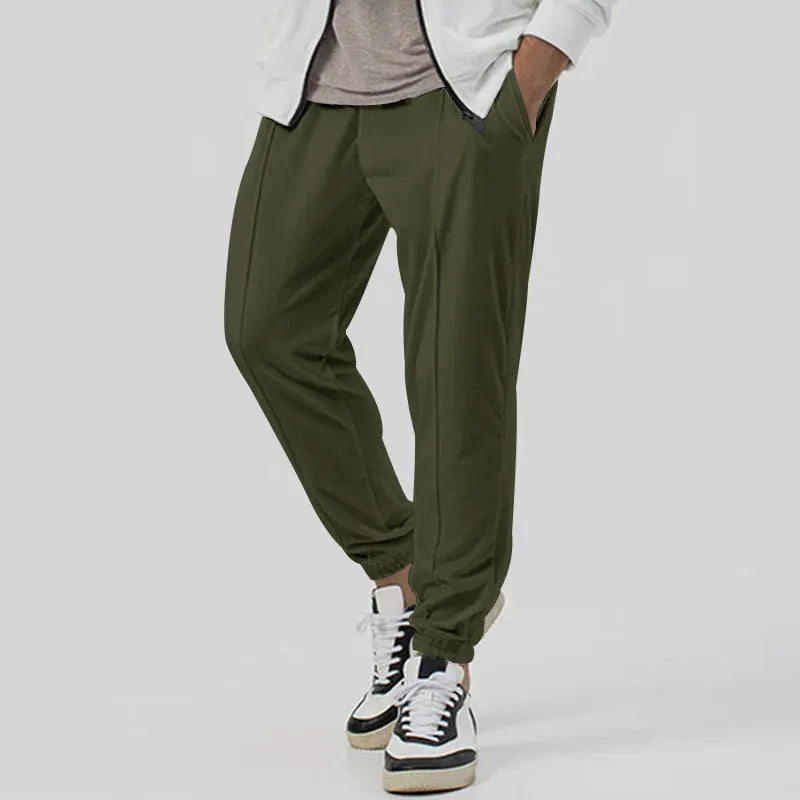 Man wearing grey loose tapered track sweatpants with a micro-elastic cotton blend fabric.