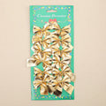 Red, gold, red gold, and silver 5 cm polyester Christmas bow ornaments on a green tree branch.