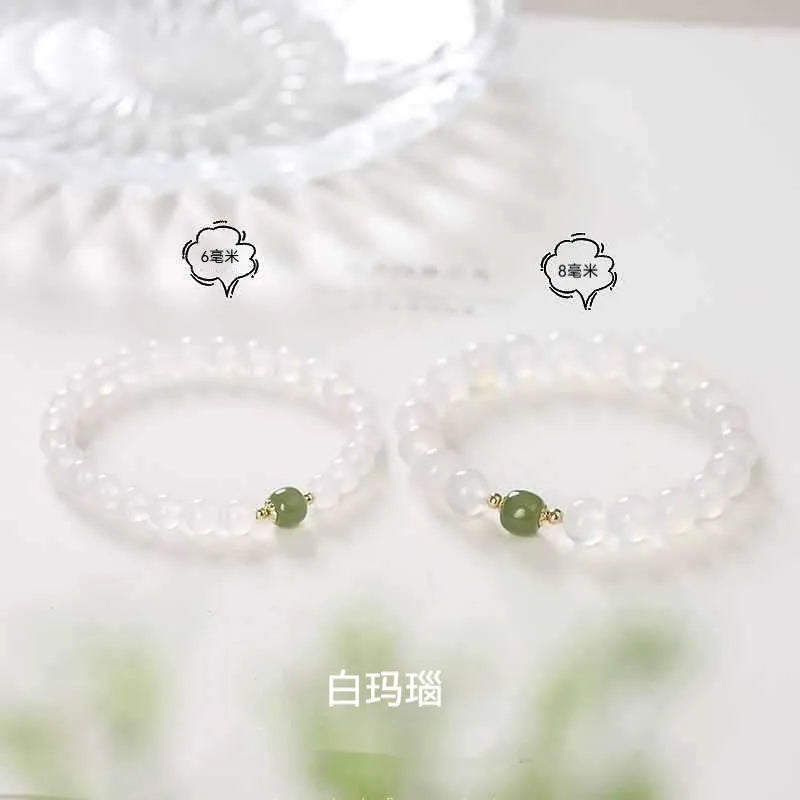 Handmade white agate crystal bracelet with cinnabar details on a wrist, showing 8mm bead size.