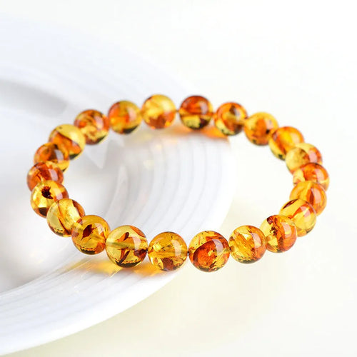 A geometric-bead amber bracelet with natural yellow piebald colouration on a wrist.
