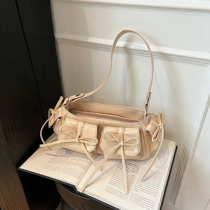 Women's pleated shoulder bag with a tassel bow, shown in multiple colours including apricot and black.