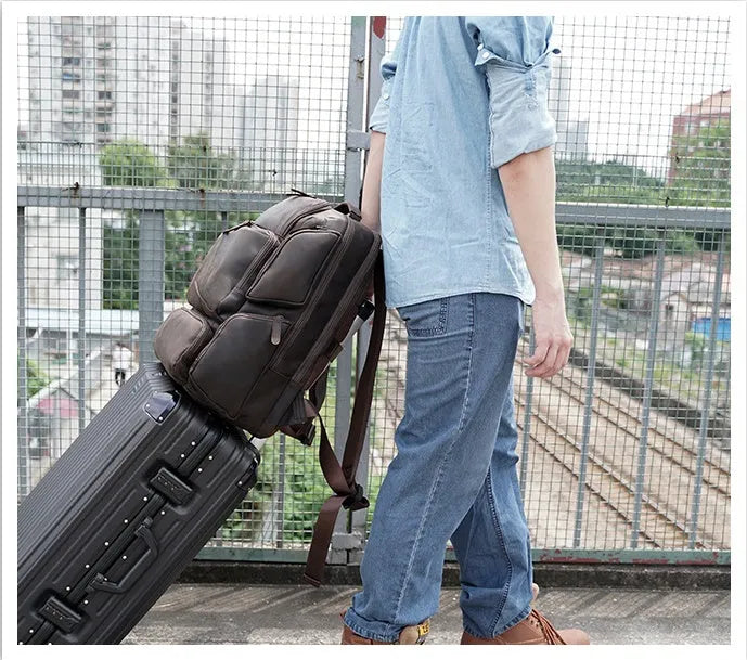 Dark brown genuine leather backpack for men showing embossed texture, double straps, and open compartments.