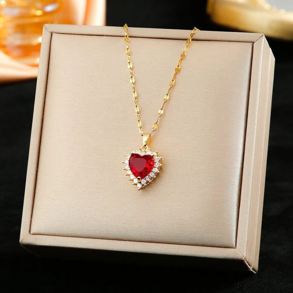 Gold-red titanium steel necklace with heart flower pendant, matching stud earrings, and ring on a grey background.