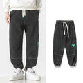 Men's loose-fit tapered cotton trousers in grey colour, shown on a model.
