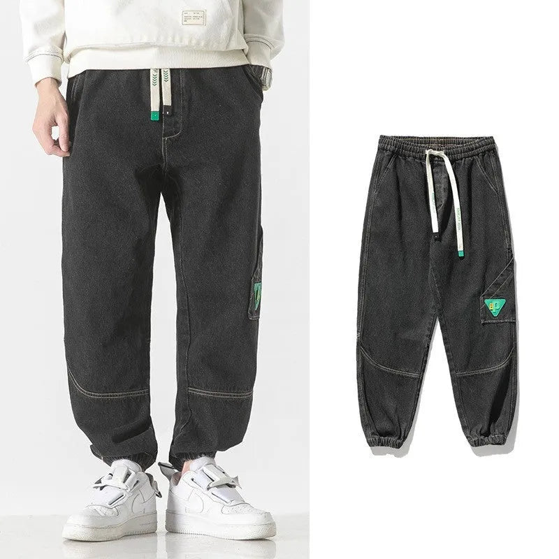 Men's loose-fit tapered cotton trousers in grey colour, shown on a model.