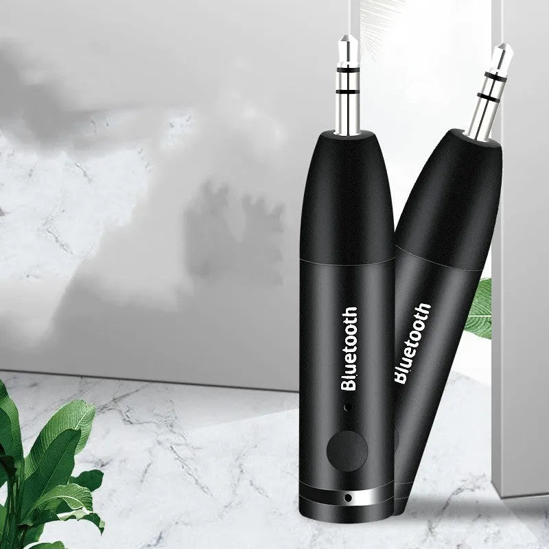 Black Bluetooth 5.0 audio receiver for car AUX or home stereo, shown with USB cable.