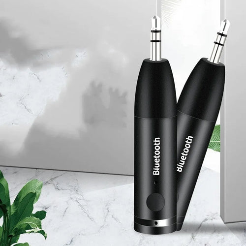 Black Bluetooth 5.0 audio receiver for car AUX or home stereo, shown with USB cable.