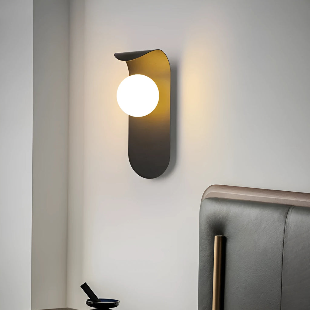 Modern minimalist wall lamp in black finish with LED warm light on a bedroom wall beside bed