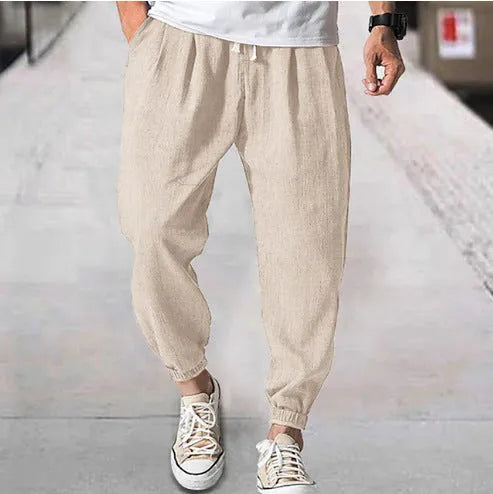 Men's loose-fit light green cotton casual trousers with a banded ankle cuff on a plain background.